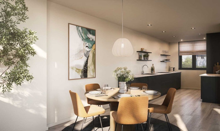 Kjøkken og spiseplass i boligbygg utviklet av WOOD Arkitekter, med rundt bord, sennepsgule stoler og svart kjøkkeninnredning.